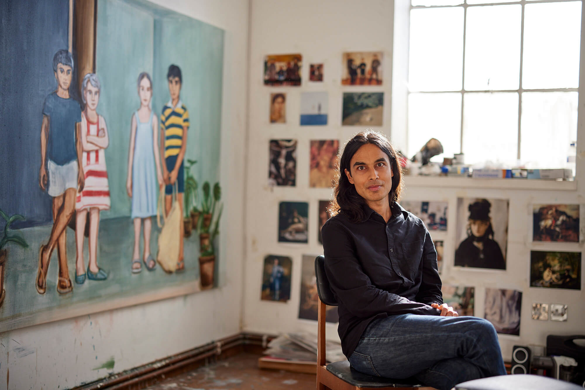 A person sitting in a chair in front of a painting.
