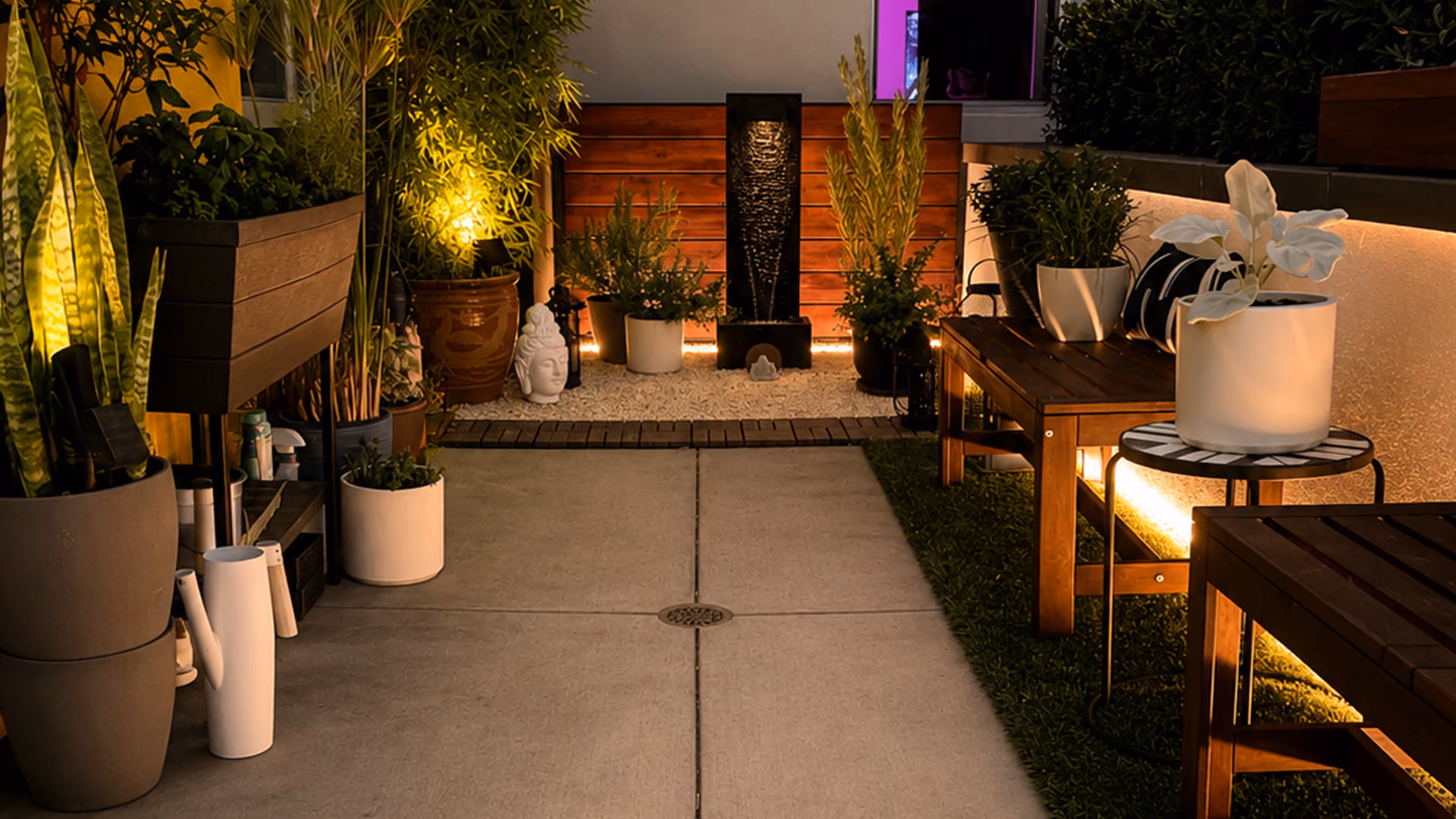 Cozy patio with glowing plants, wooden benches, round table, and a decorative Buddha head statue.