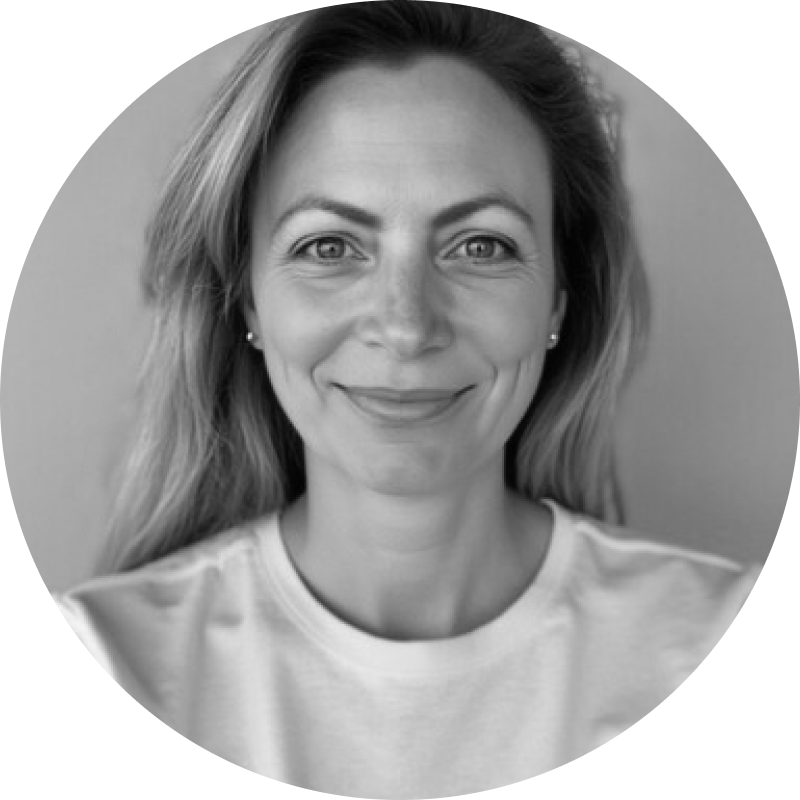 Black and white close-up portrait of a smiling woman with long hair wearing a light-colored shirt.