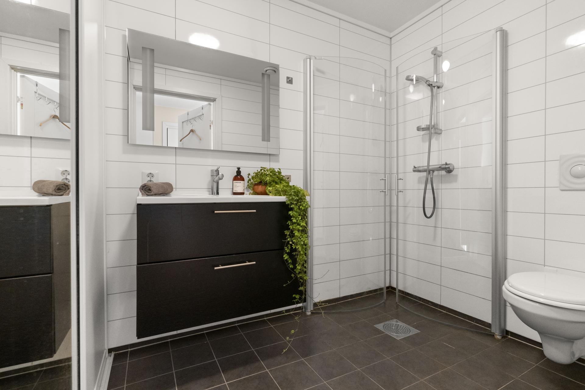 - Badet har flislagt gulv med varmekabler, baderomsplater på vegg og malt gips i himling -