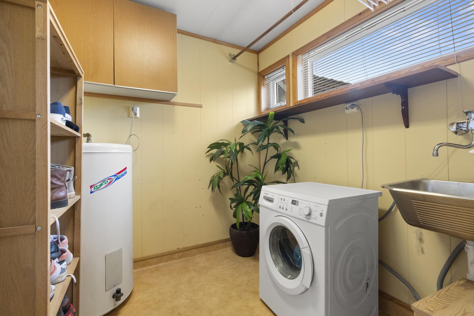 - Praktisk vaskerom ved siden av badet med belegg på gulv og plater på vegg -