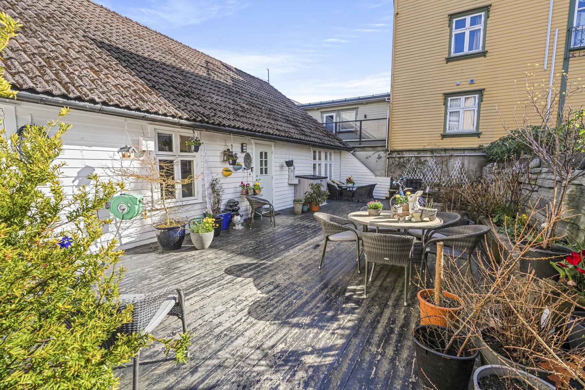 - Boligens bakside med inngang til leiligheten. Stor terrasse på 85 m2 med gode solforhold - 