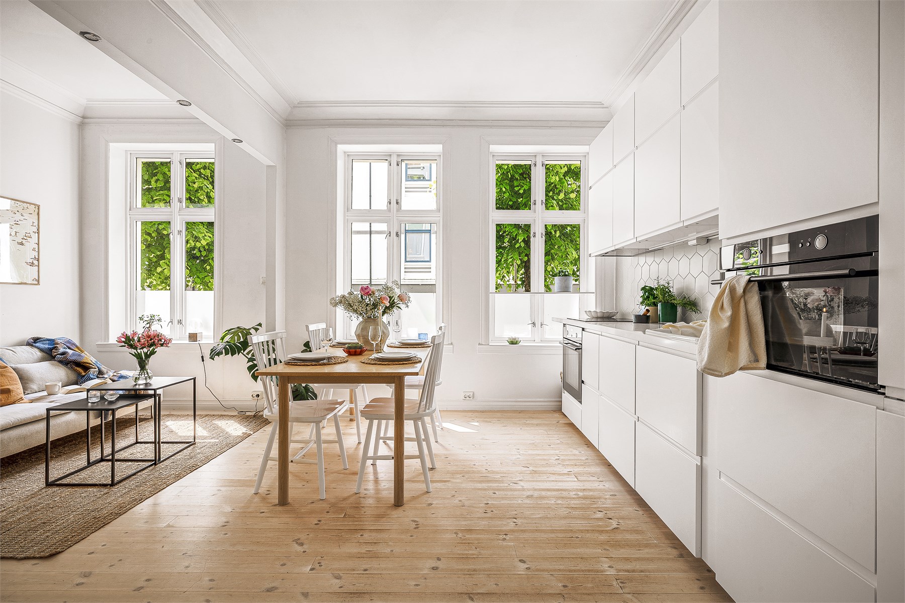 Stuens størrelse gir god plass til både sittegruppe og spisestue. Det er verdt å merke seg at de frodige omgivelsene fra gaten følger deg inn i boligen.