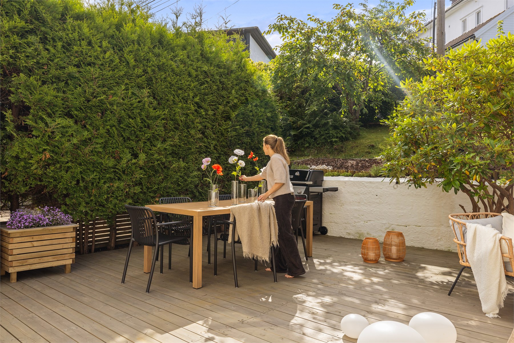 Den grønne innrammingen skaper en lun og hyggelig atmosfære på terrassen, og gir uteplassen en skjermet og behagelig ramme, perfekt for lange, fine sommerdager.