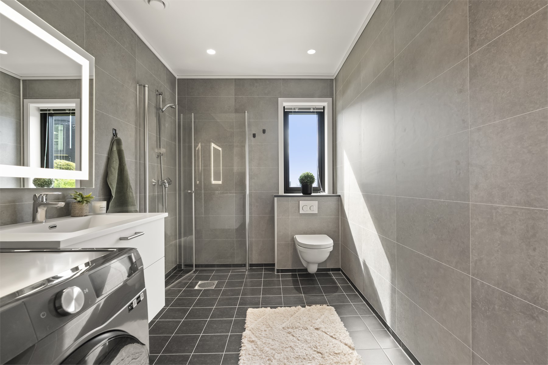 - Badet har flislagt gulv med gulvvarme, baderomsplater på vegger og malte flater i himling med downlights -