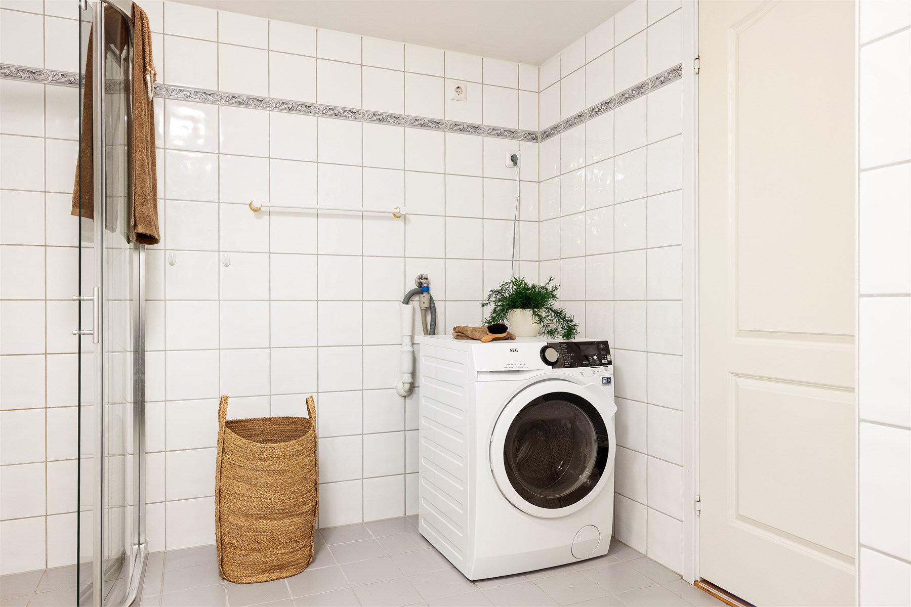 Badet er innredet med toalett, helstøpt servant med skuffer under,  dusjdører i klart glass og opplegg for vaskemaskin. 