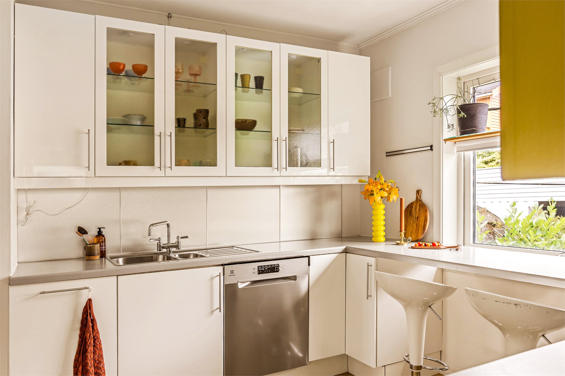 Kjøkkenet har en praktisk innredning med slette fronter, hvor to av overskapene har dekorative glassfronter og laminat benkeplate. 
