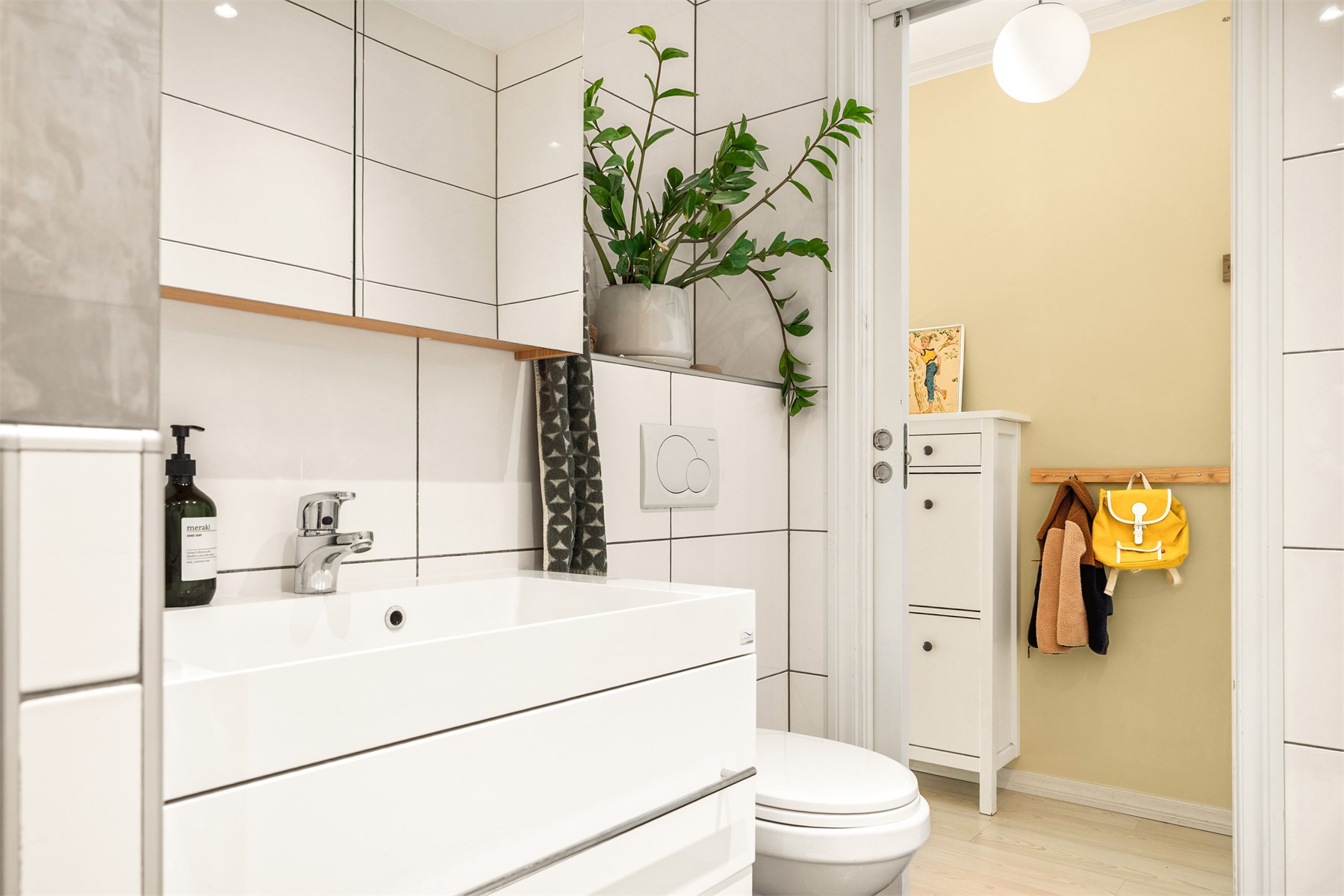 Badet inneholder vegghengt toalett, helstøpt servant med skuffer under og dusjdører i klart glass. 