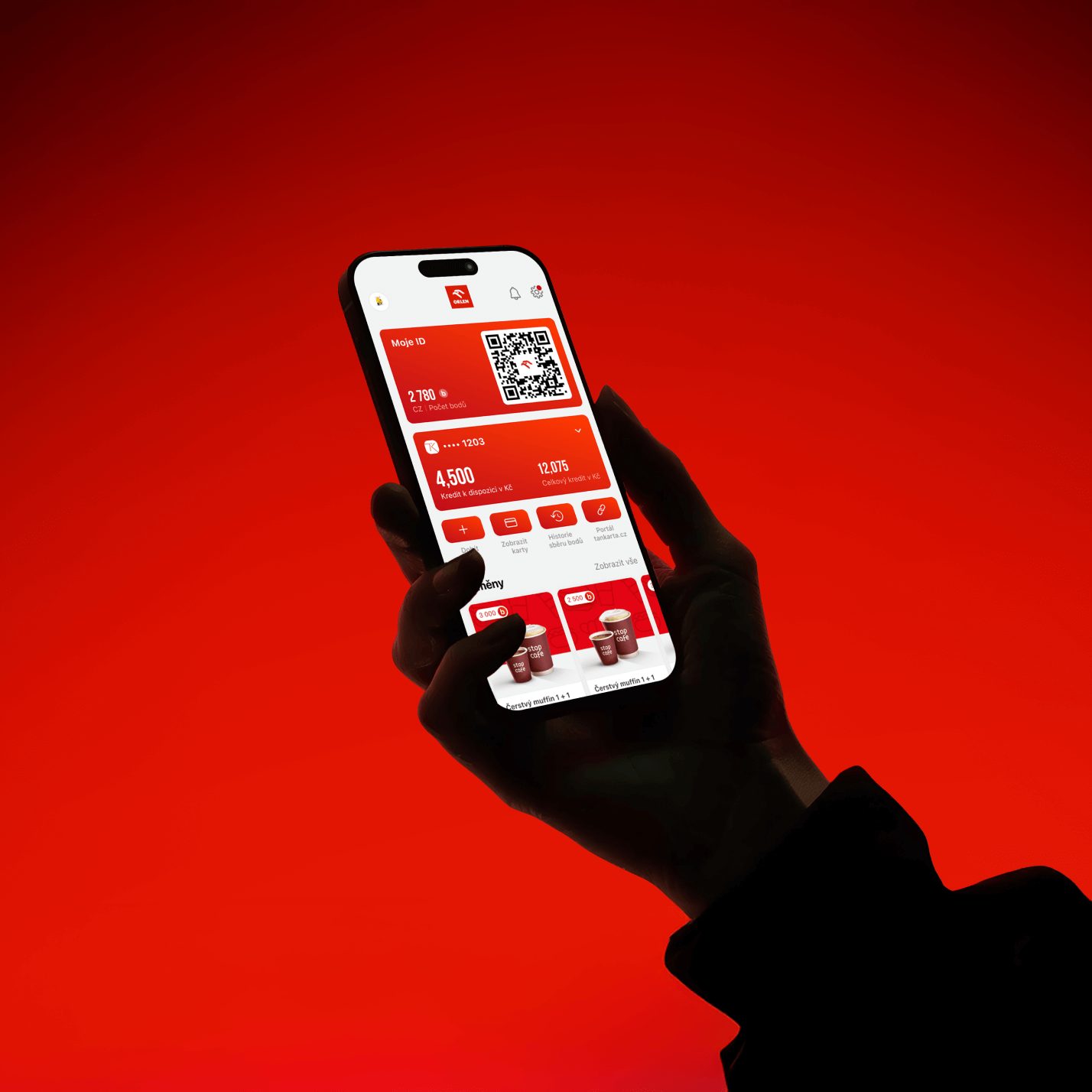 Hand holding a smartphone displaying a red-themed app interface with QR code, points balance, and coffee menu offers.