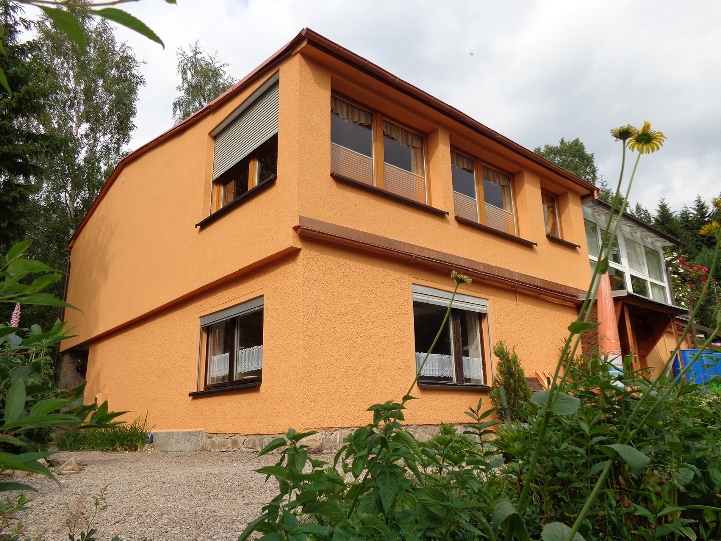 Erfolgreich abgeschlossene Fassadendämmung an einem Wohnhaus. Der neue orangefarbene Außenputz schützt die Dämmung.