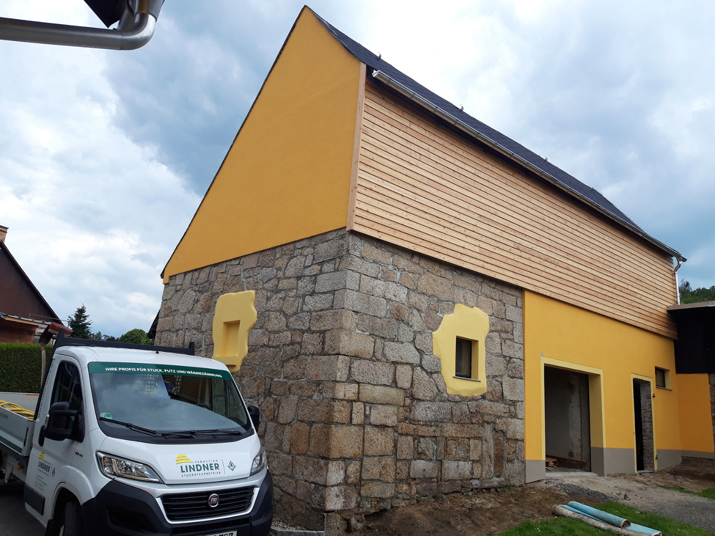 Fachgerechter Außenputz am Giebel eines Nebengebäudes, harmonisch abgestimmt auf das bestehende Naturstein-Mauerwerk.