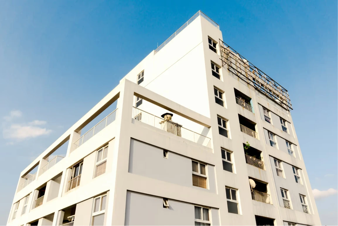 Bâtiment résidentiel blanc moderne de plusieurs étages sous un ciel bleu clair.