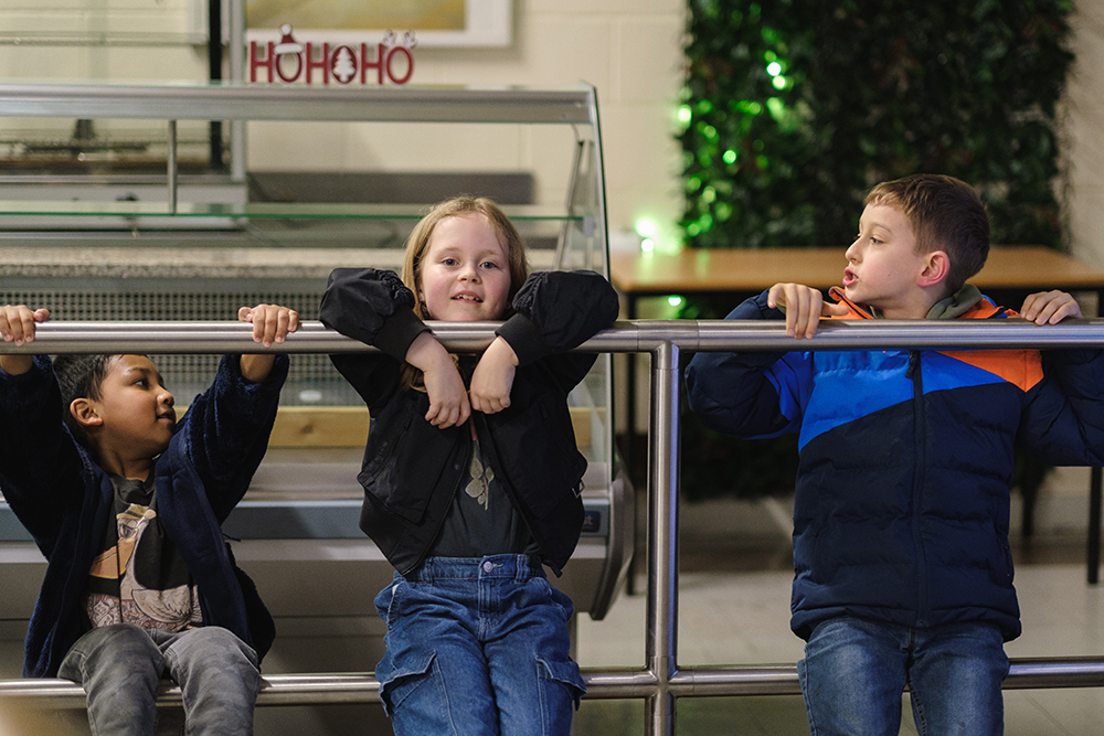 Three young chess club members hang out together at the chess club.
