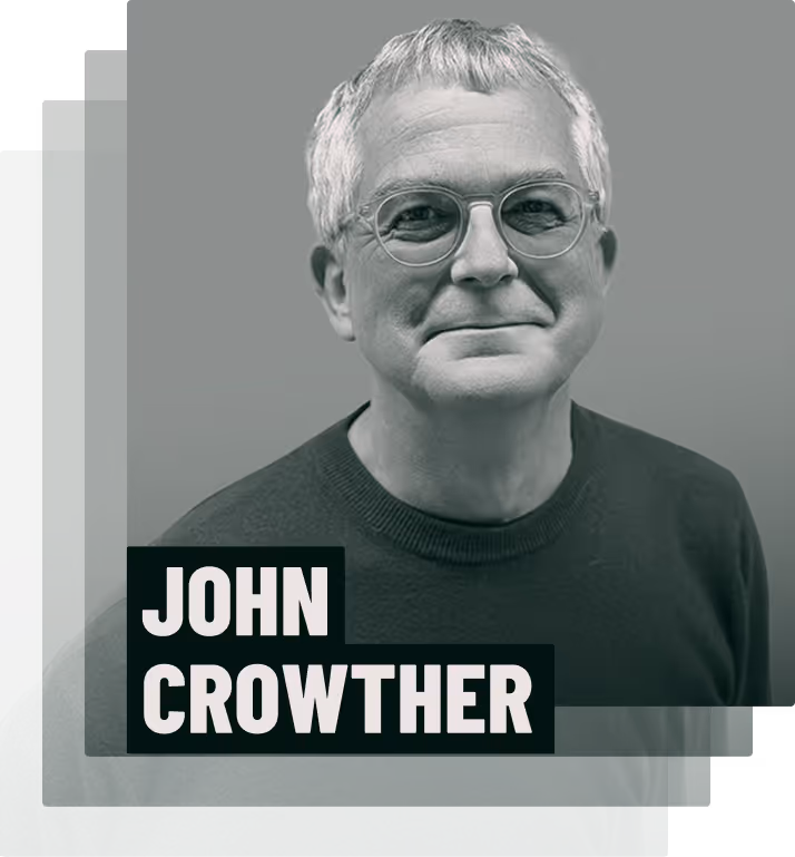 Black and white portrait of an older man with short gray hair, glasses, and a dark sweater, labeled John.