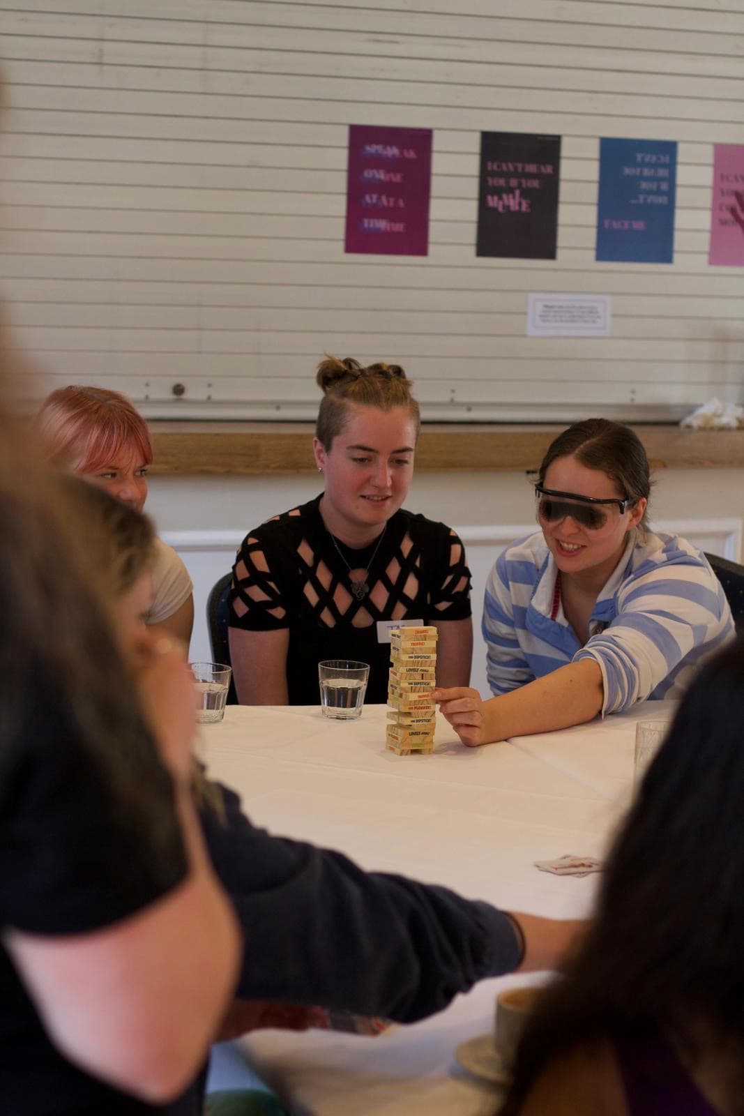 Colleagues sit around a table with a game of jenga in the middle. One colleague is blind-folded. Part of an Accessibility and Inclusion training.