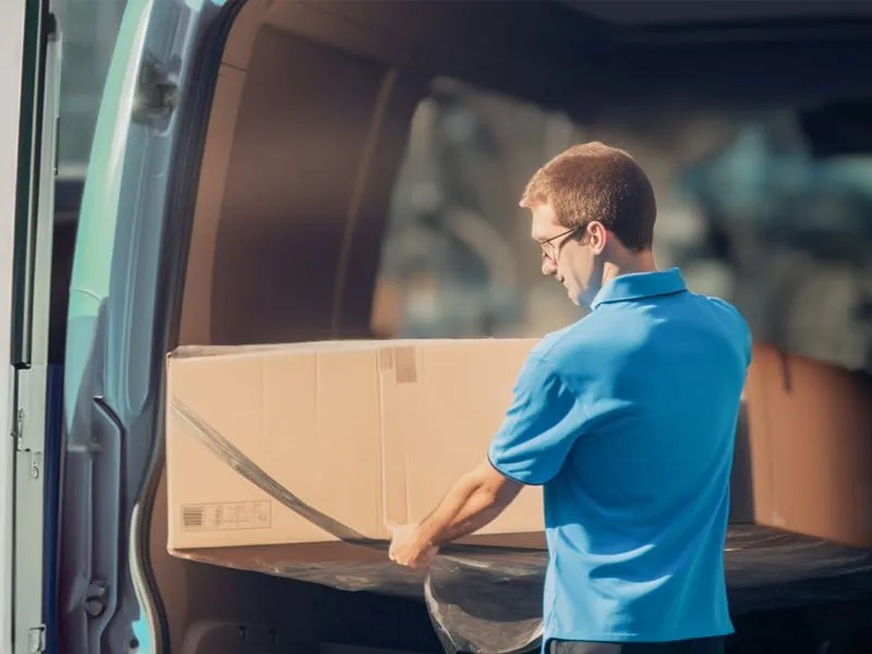 Man loading large mirror onto van
