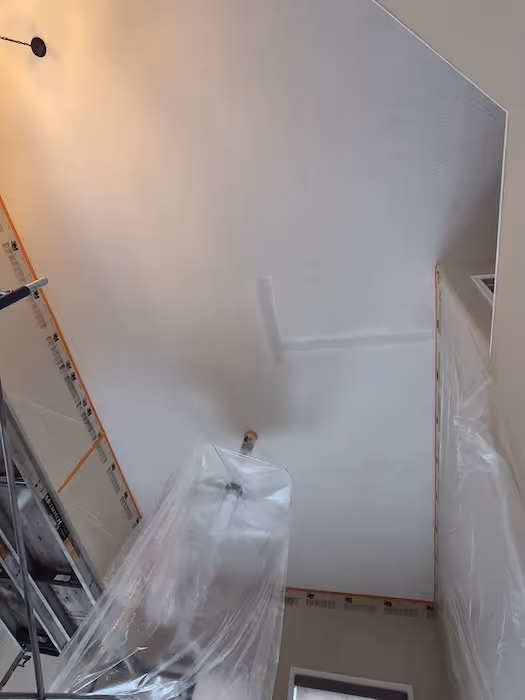Ceiling with taped and patched drywall repair, areas around covered with plastic sheets.