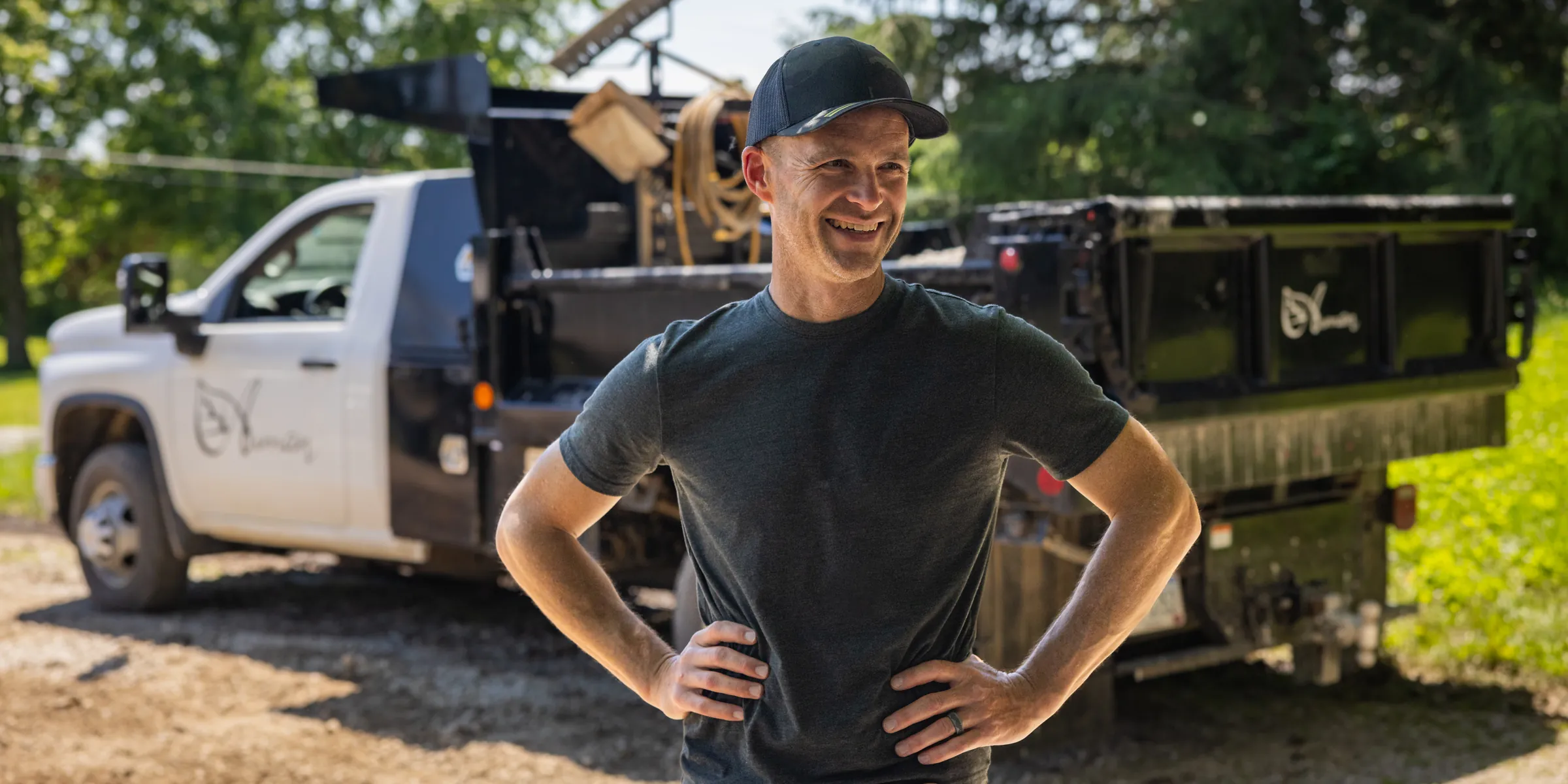 Caleb Auman smiling beside the Auman Outdoor trucks