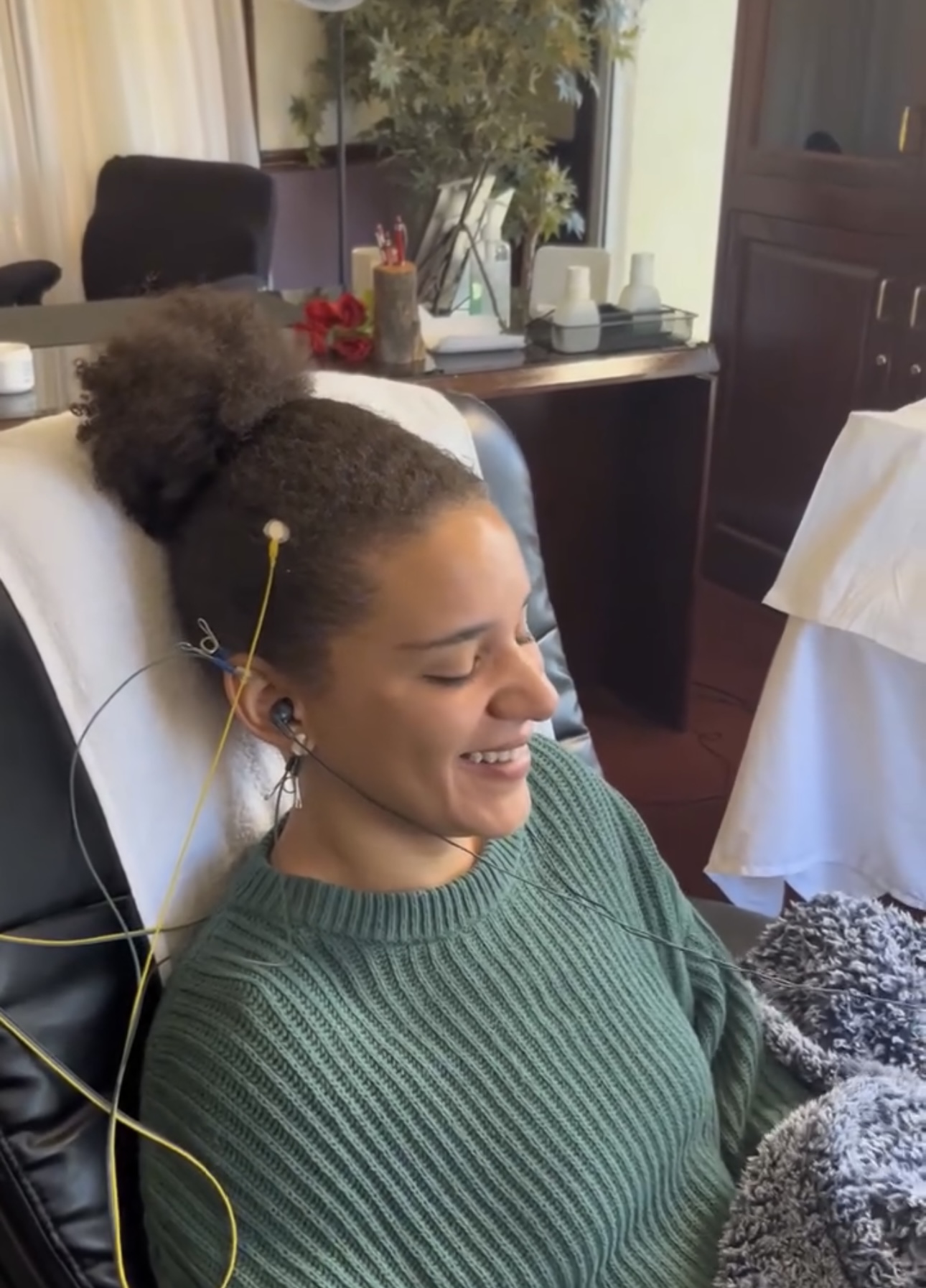 Young boy sleeping in a chair wearing a gray shirt with ear electrodes attached by wires for monitoring.
