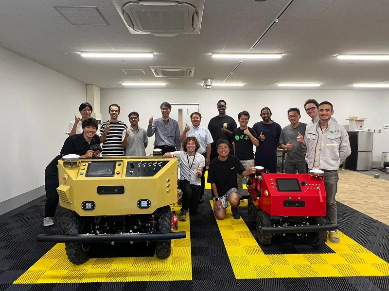 Diverse group of young adults posing indoors in front of a vintage cabinet and chandelier.