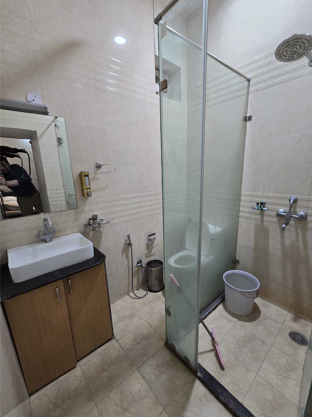 A clean bathroom with a showerhead, a sink with a mirror, and white tiled walls.