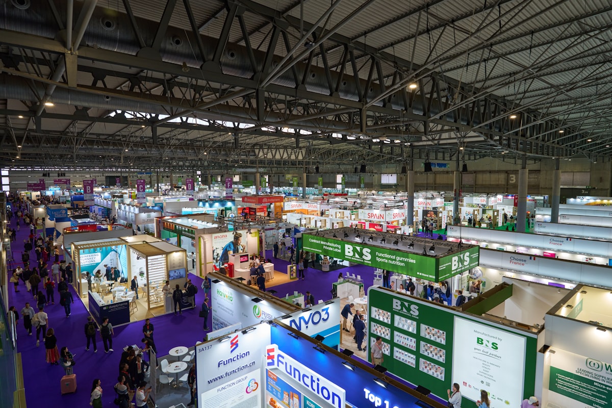 A busy indoor exhibition hall full of trade show stands