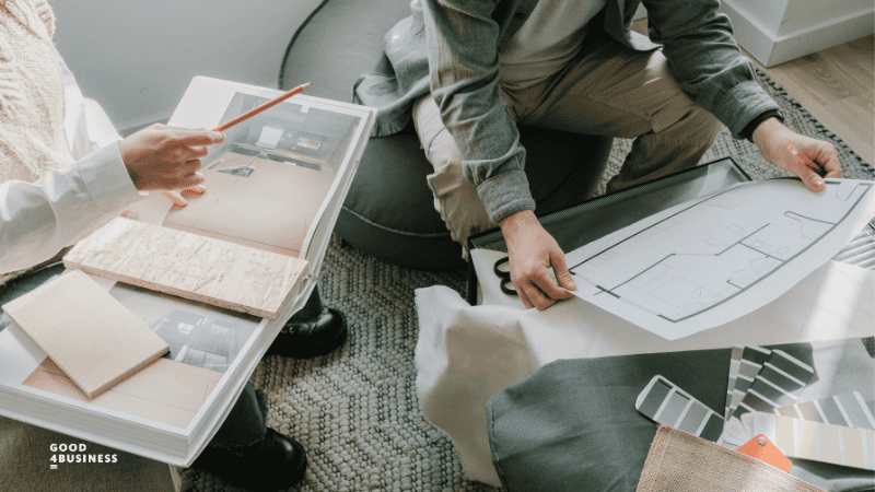Female Designer and male client looking at floor plan and colour samples