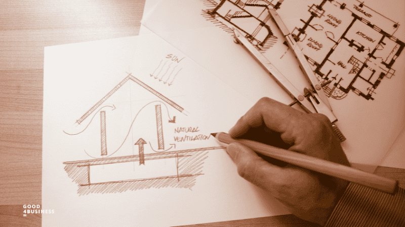 House plan on timber table with line drawing of house illustrating natural ventilation with hand holding timber pencil and a device for drawing circles