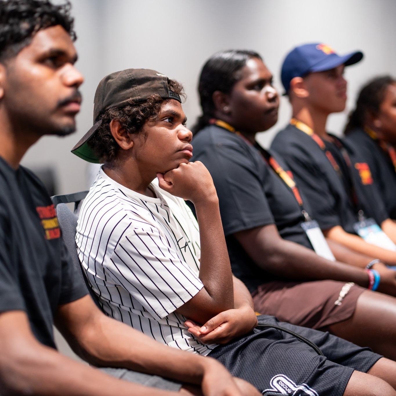 A group of young people sitting attentively in a row during an event or meeting.