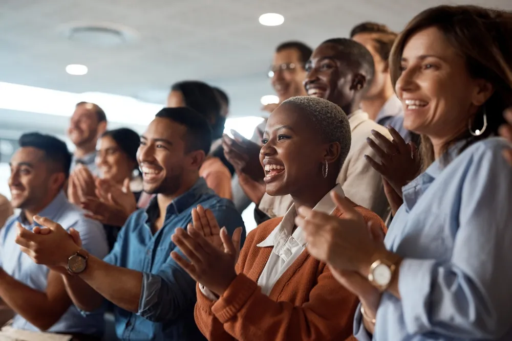 Diverse group of people smiling and clapping during an event.