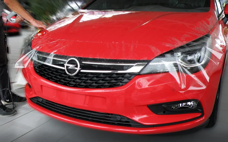 Montage einer transparenten Steinschlagschutzfolie auf der Front eines Autos