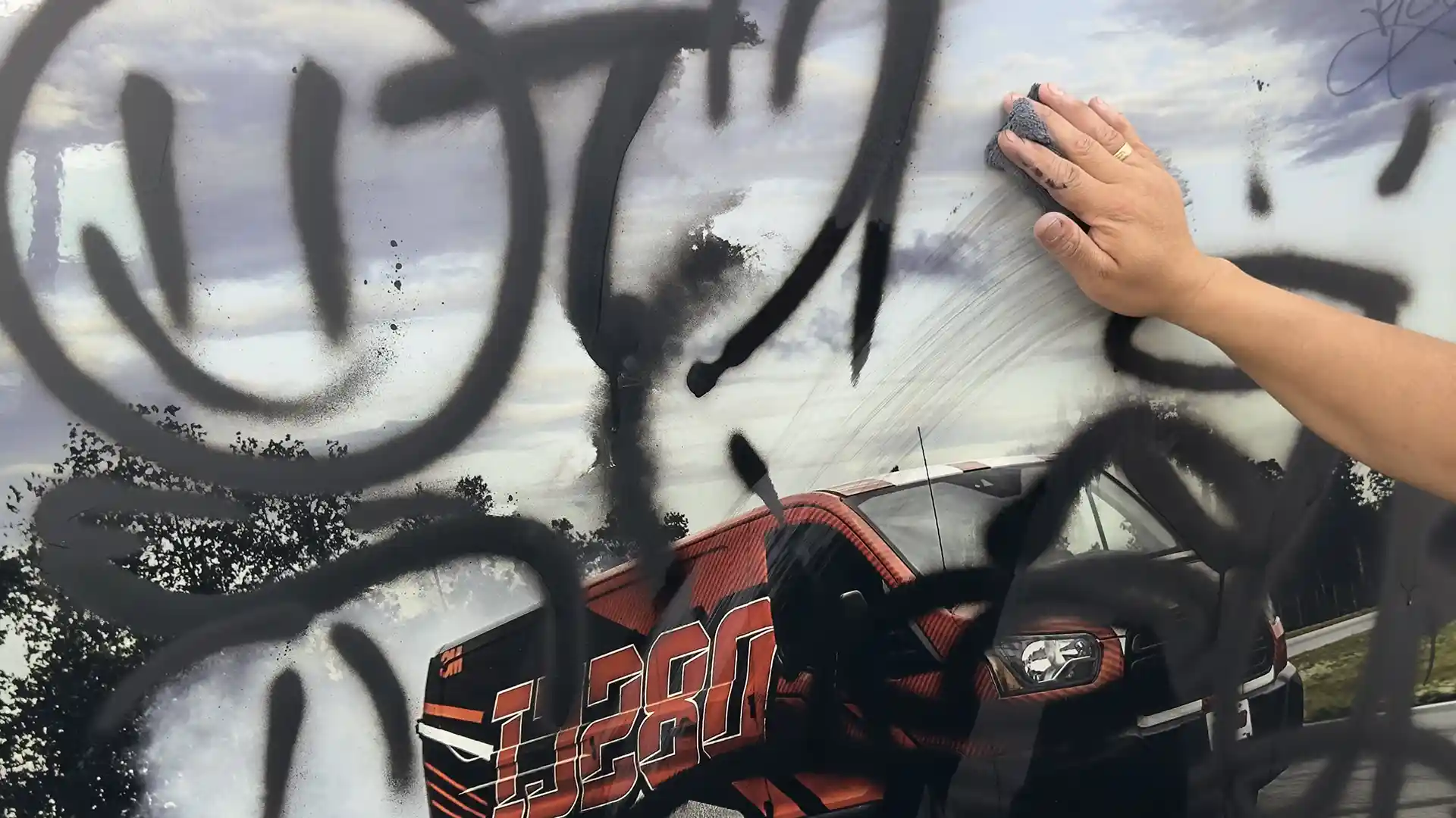 Mann entfernt Graffiti mit einem Tuch von einer Oberfläche – Demonstration der einfachen Reinigung durch Anti-Graffiti-Folie