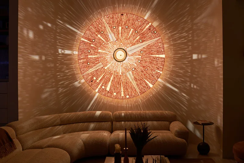 Modern living room with curved beige sofa and a large circular light fixture casting radial patterns on the wall.
