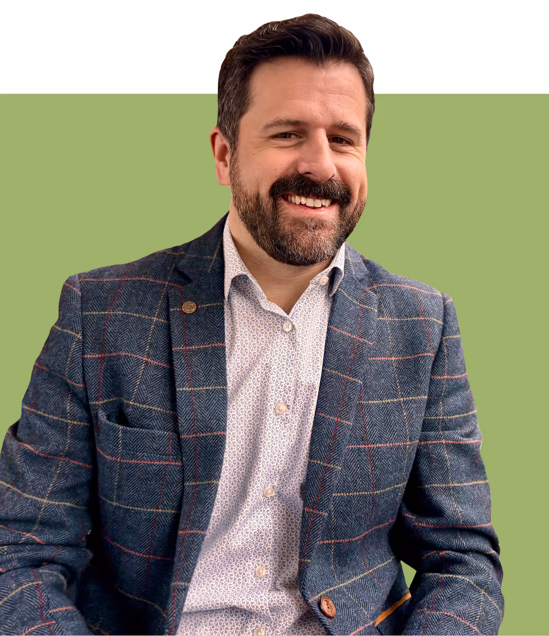 Smiling man with a beard wearing a patterned blazer and white shirt against a green background.