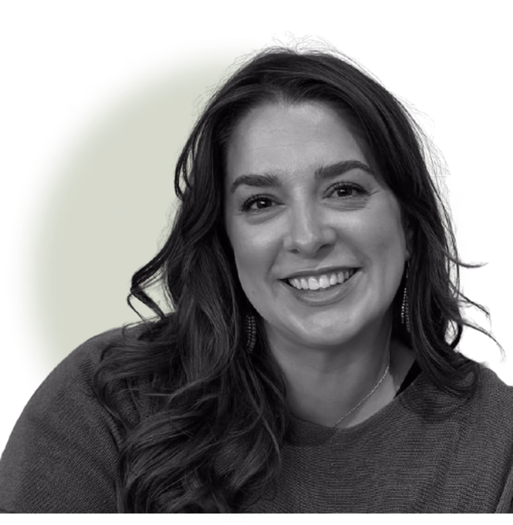 Smiling woman with long wavy hair wearing a sweater and earrings against a green circle background.