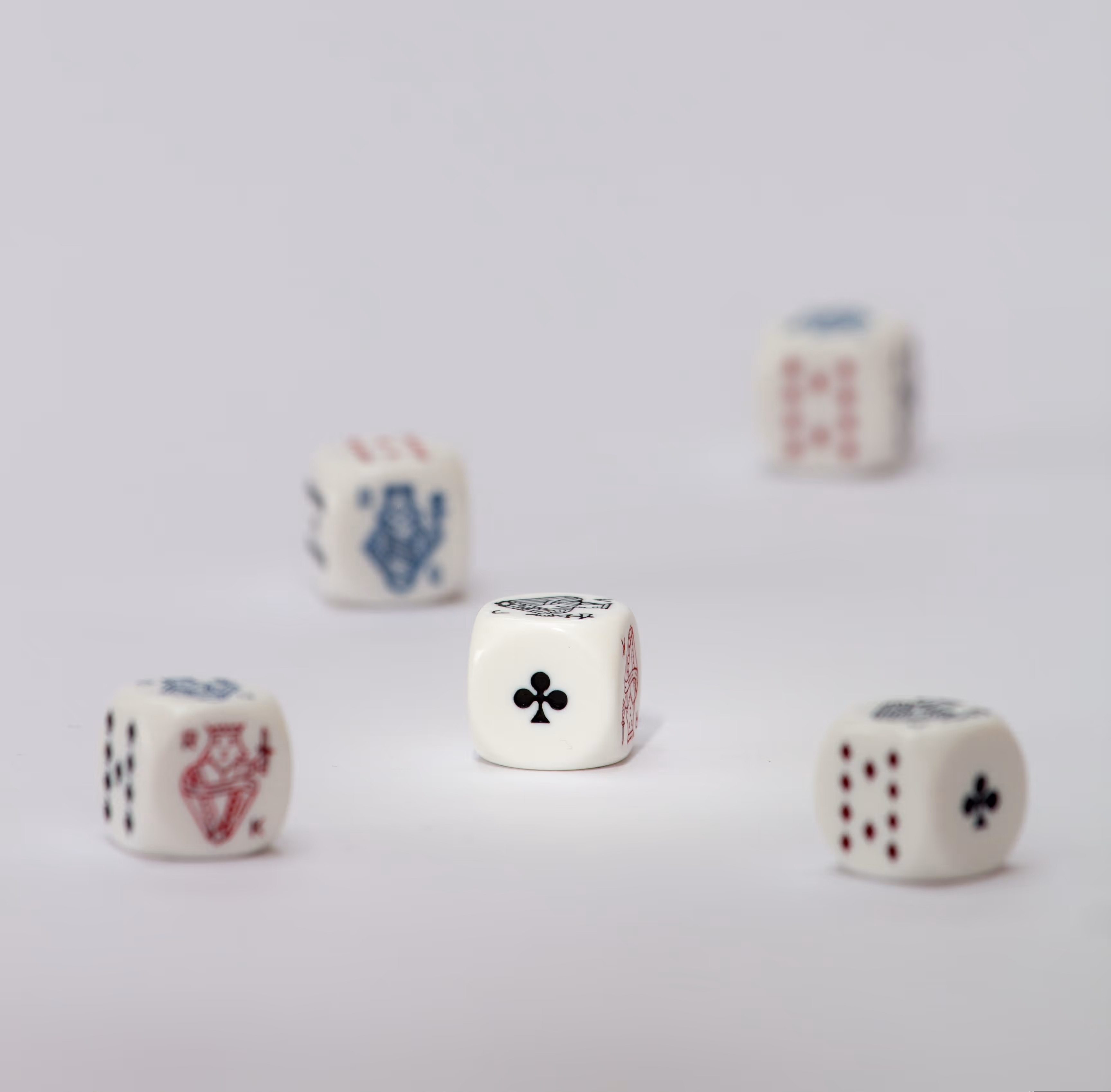 Белые игральные кости с символами из игральных карт на светлом фоне, кость с крестовой мастью в центре.