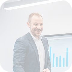 Smiling man in business attire standing in front of a screen displaying a blue bar chart.