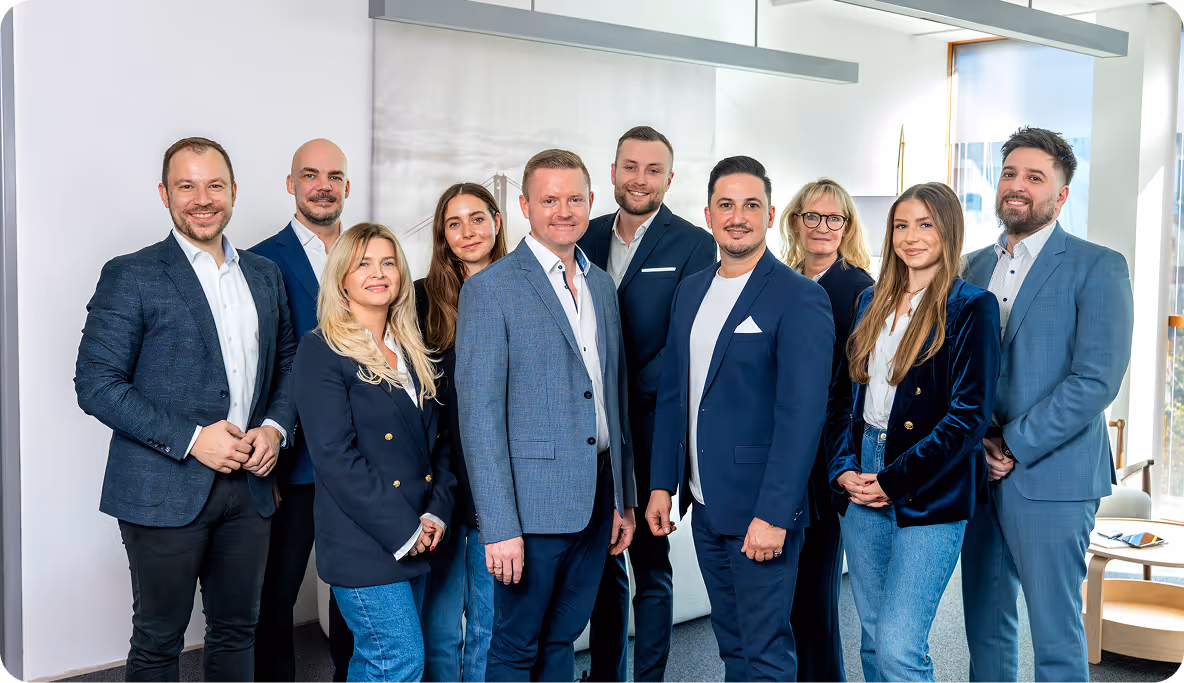 Group of 10 professionally dressed men and women standing indoors, smiling at the camera.