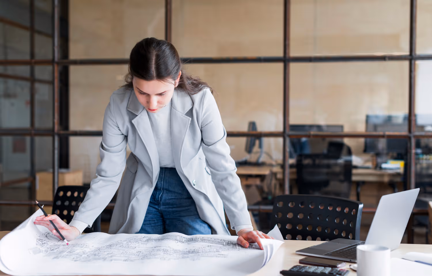 Ingenieurin prüft Baupläne am Tisch – Projektabstimmung und statische Planung