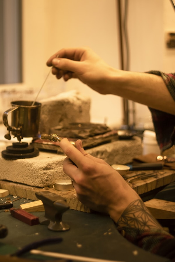 A man with tattoed hands making crafts with copper bit.