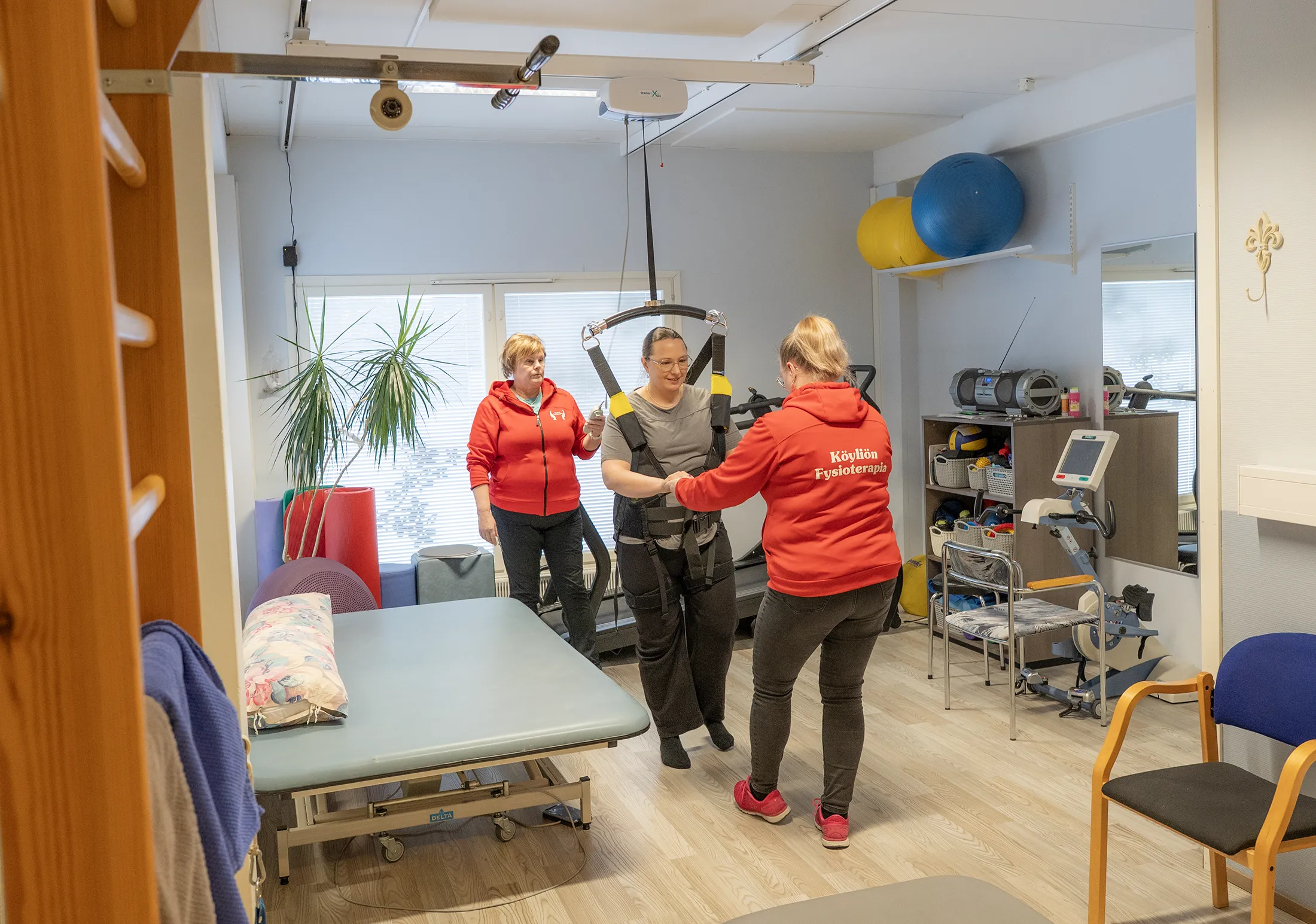 Kaksi naista ohjaamassa kolmatta avustetun kävelyn laitteessa