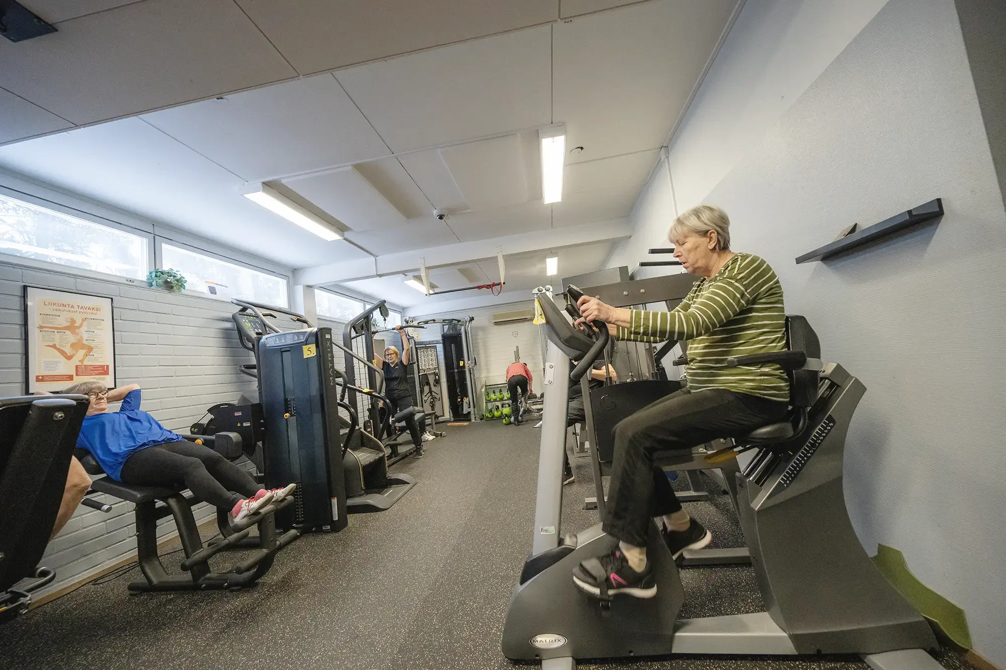 Ryhmä ihmisiä kuntoilemassa kuntosalilla yhdessä.