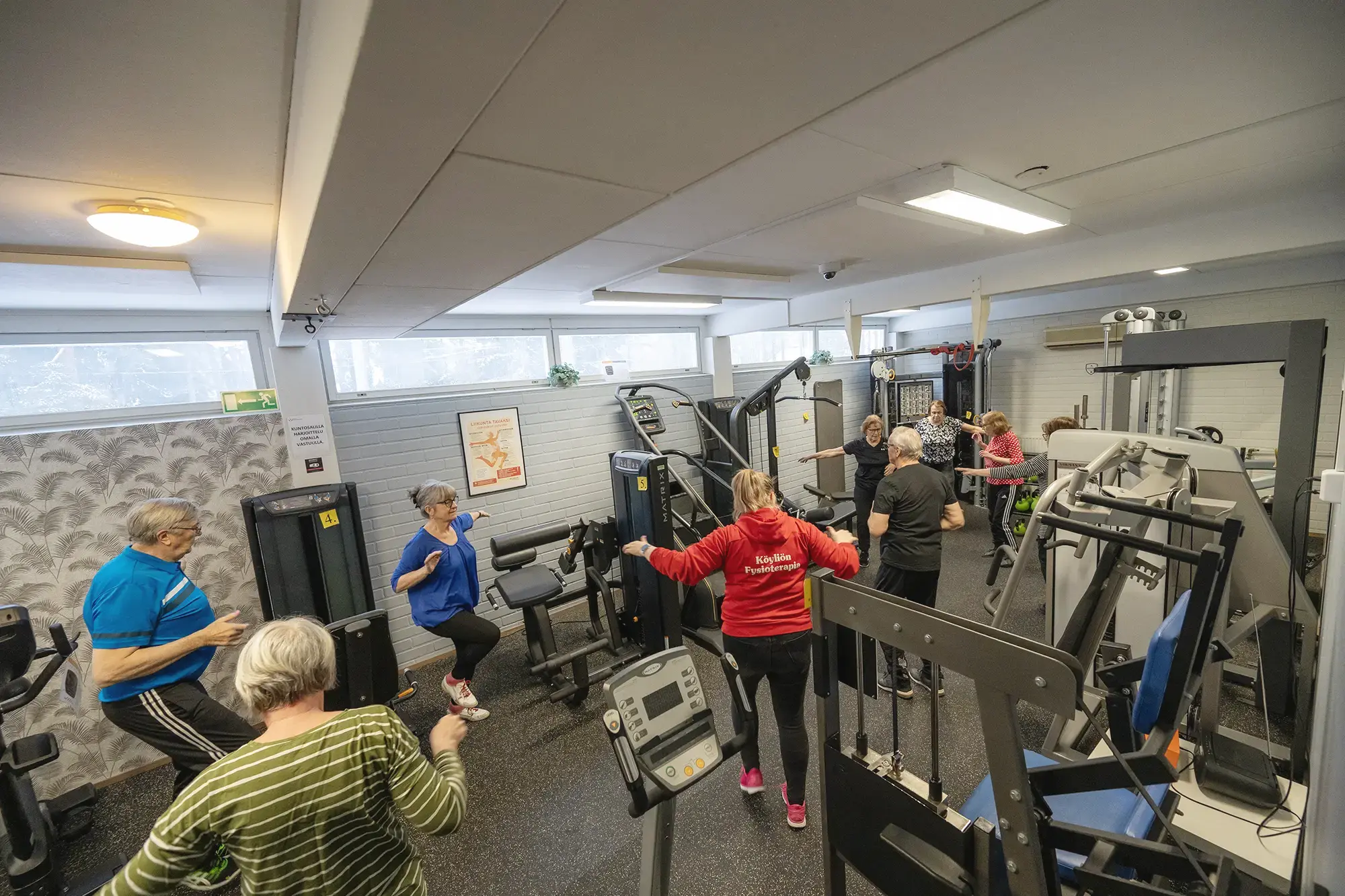 Ryhmä ihmisiä kuntoilemassa kuntosalilla yhdessä.