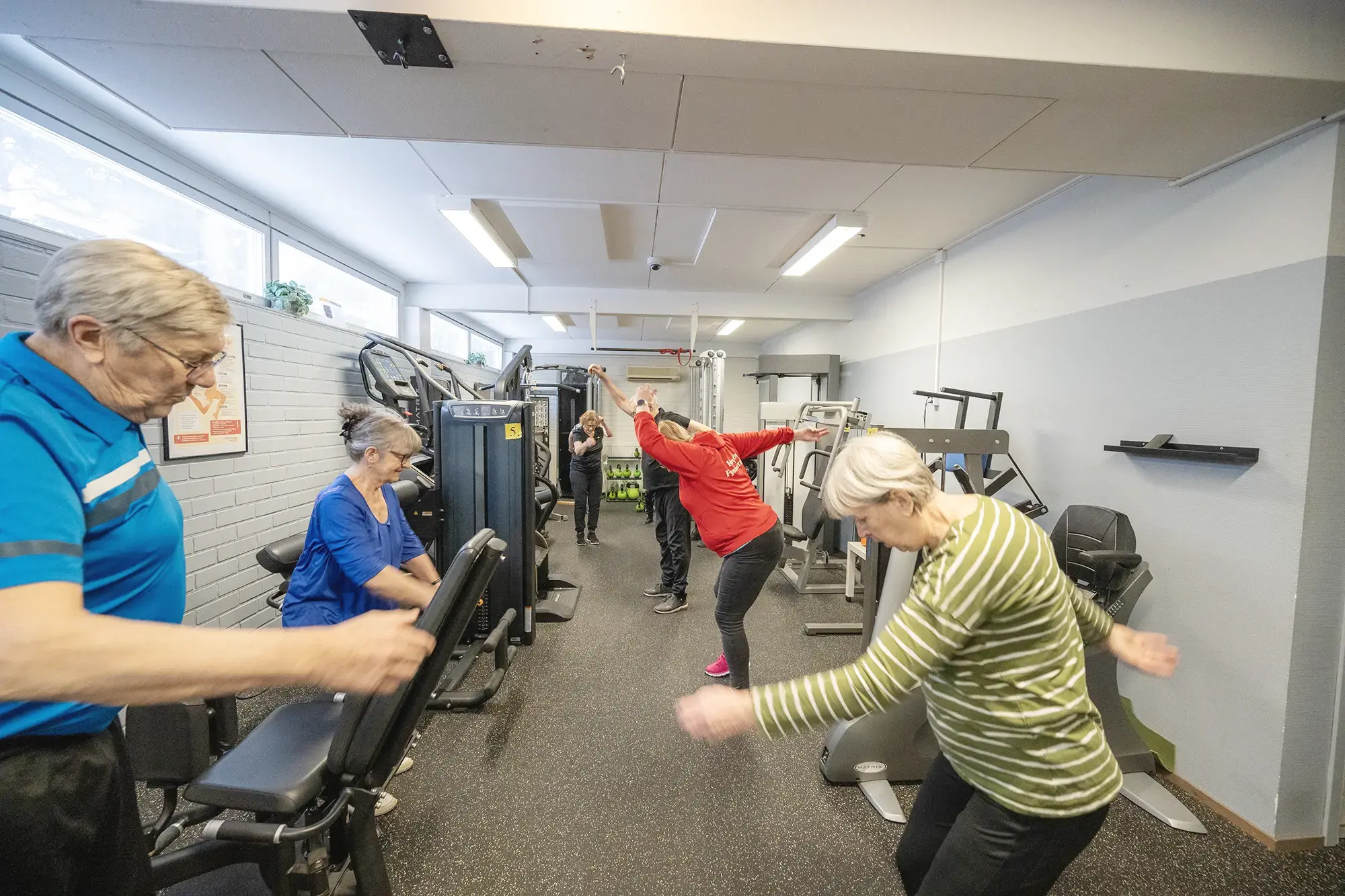 Ryhmä ihmisiä kuntoilemassa kuntosalilla yhdessä.