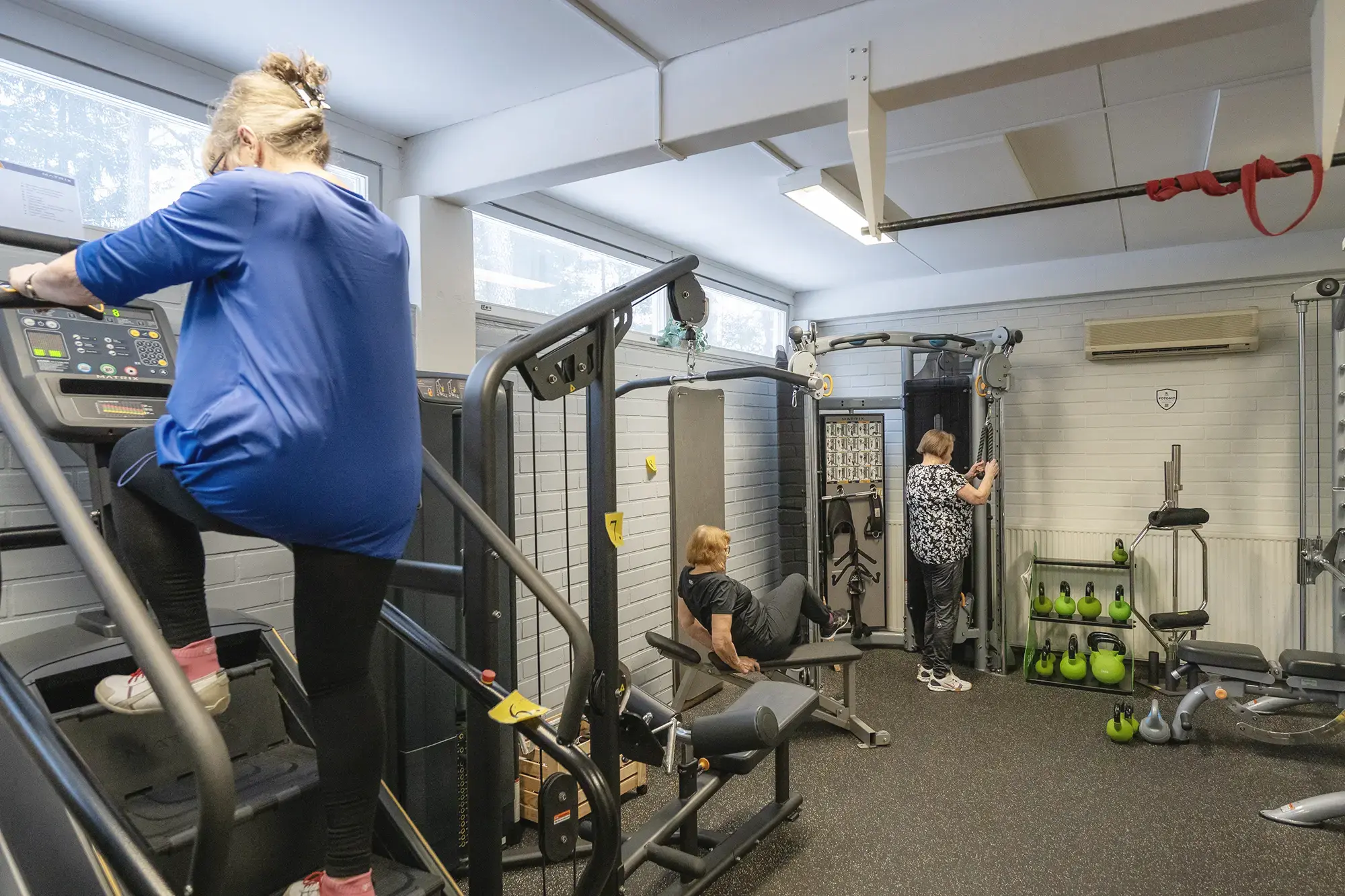 Ryhmä ihmisiä kuntoilemassa kuntosalilla yhdessä.