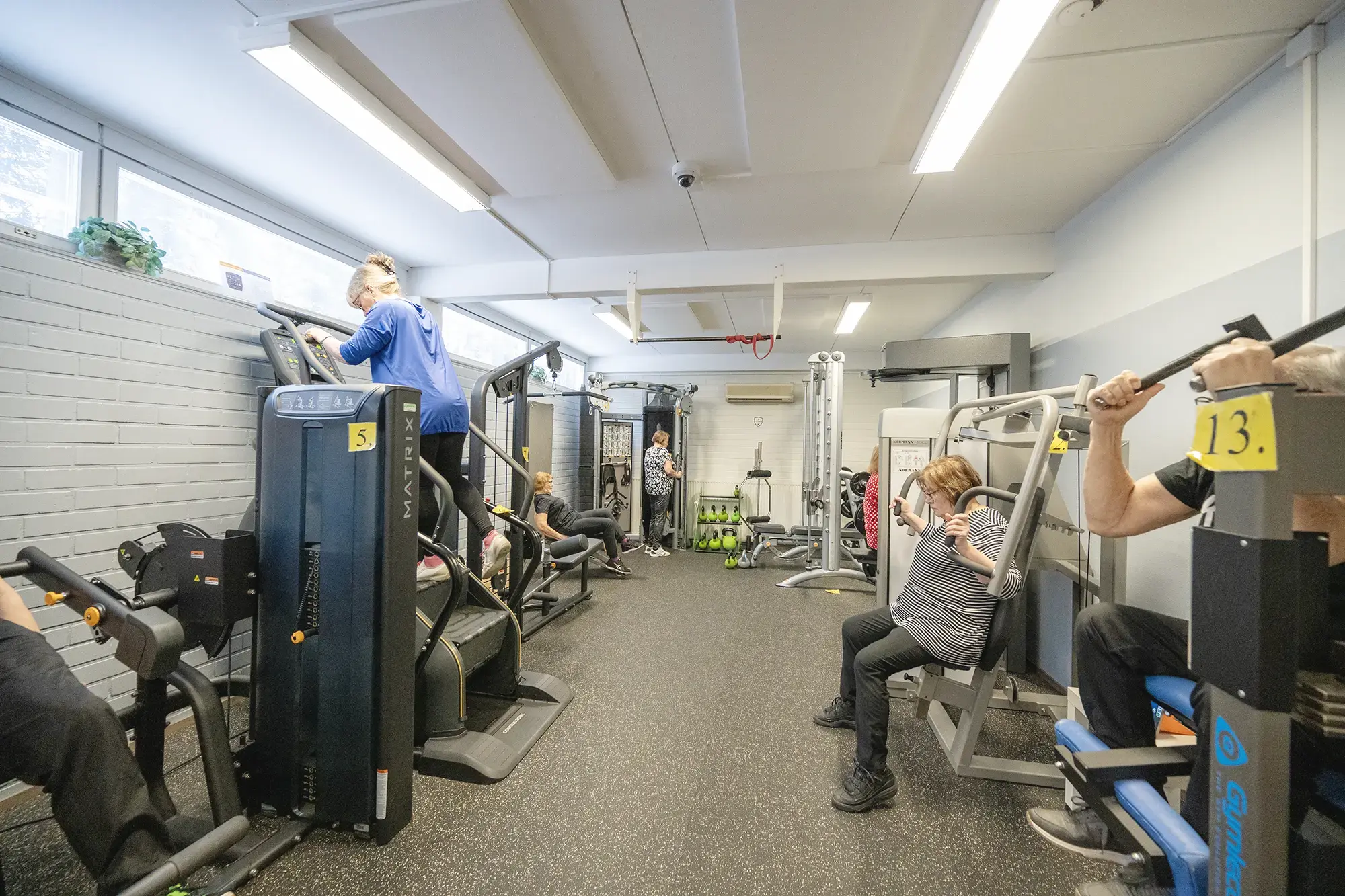Ryhmä ihmisiä kuntoilemassa kuntosalilla yhdessä.