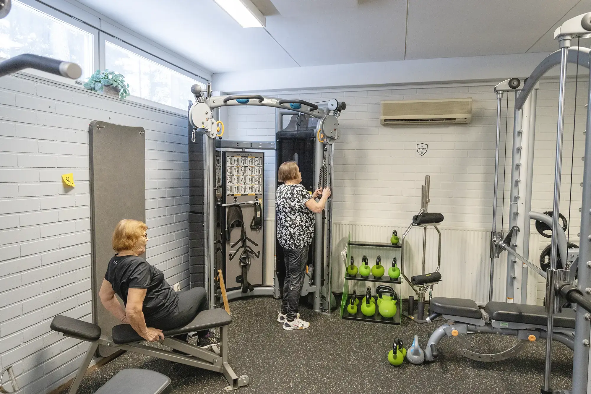 Ryhmä ihmisiä kuntoilemassa kuntosalilla yhdessä.