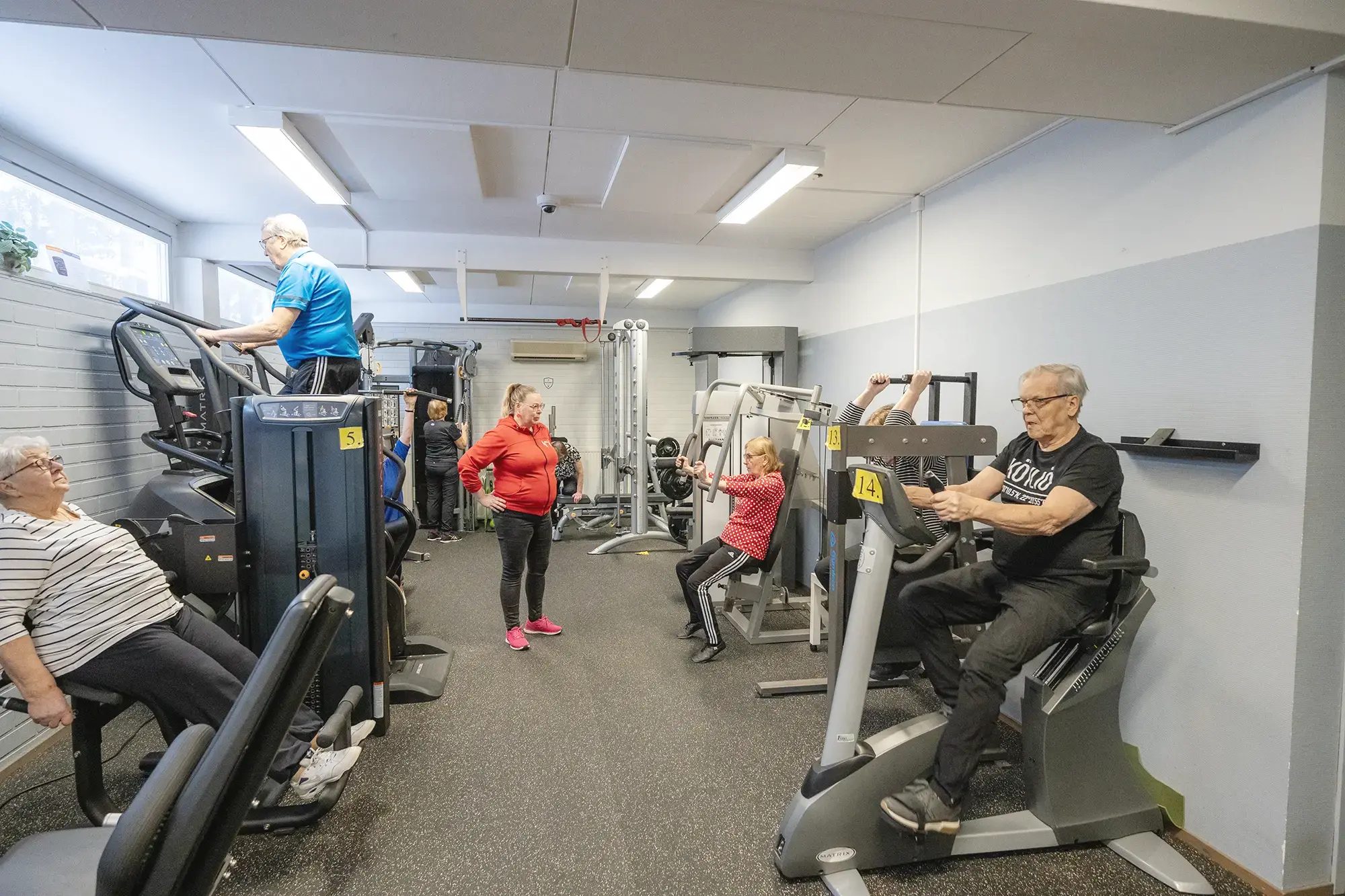 Ryhmä ihmisiä kuntoilemassa kuntosalilla yhdessä.