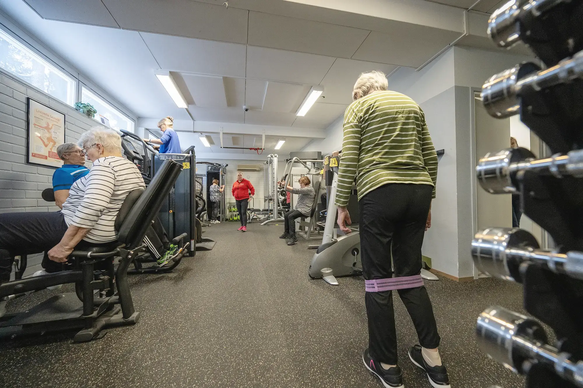 Ryhmä ihmisiä kuntoilemassa kuntosalilla yhdessä.