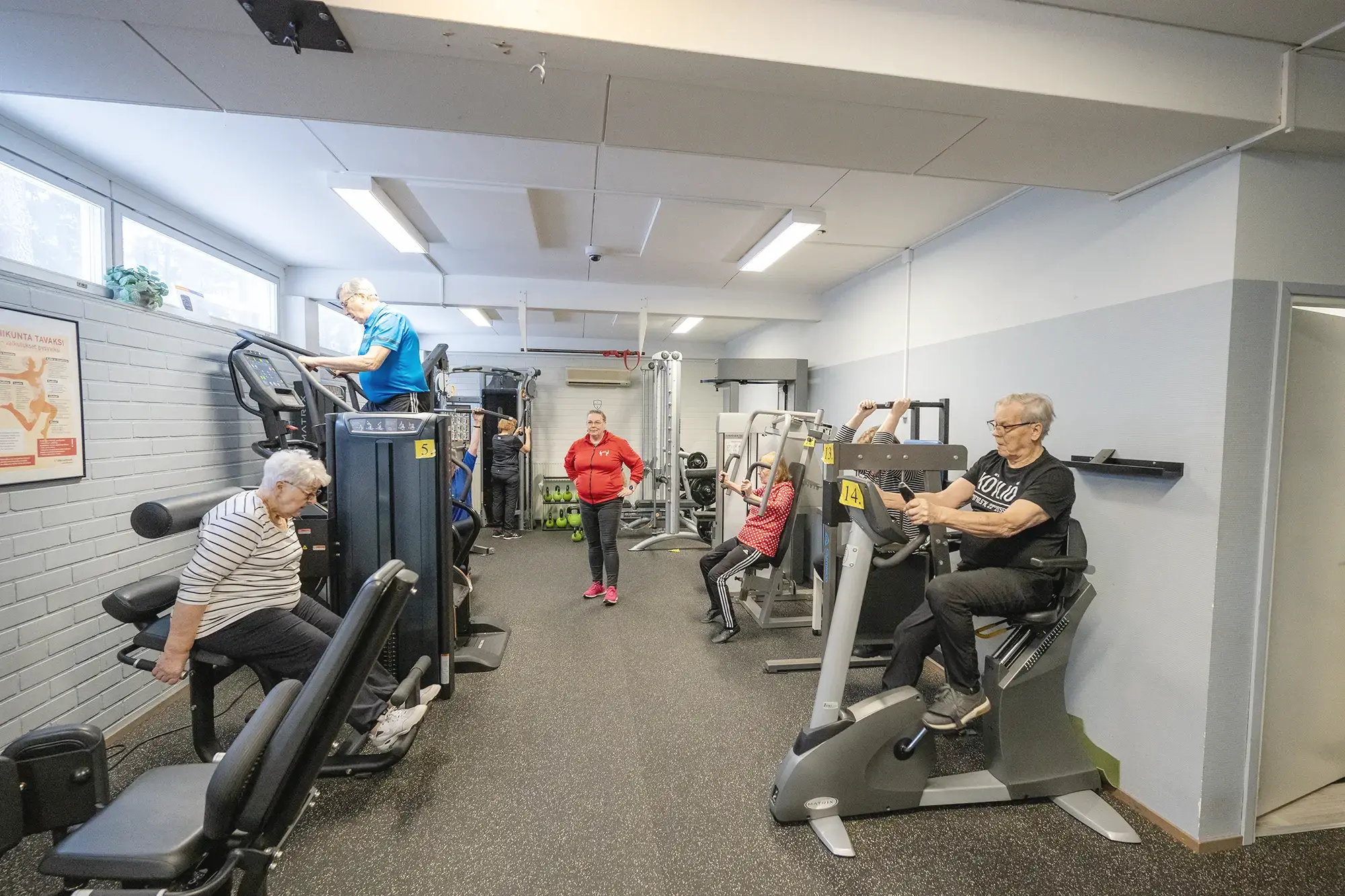 Ryhmä ihmisiä kuntoilemassa kuntosalilla yhdessä.